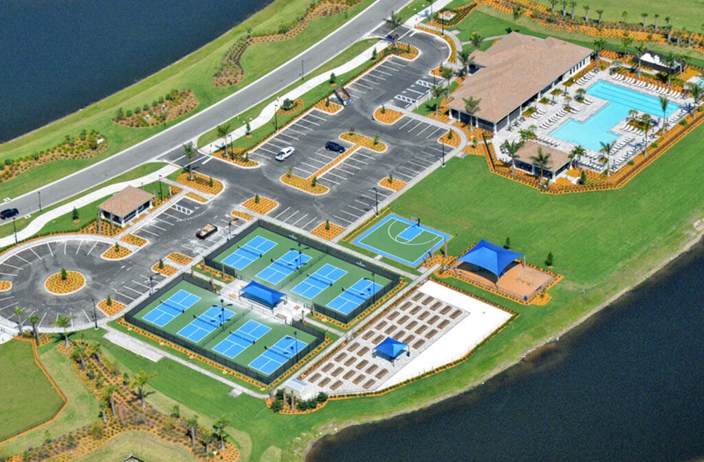 An arial view of the clubhouse parking lot, a swimming pool, half a basketball court and four tennis courts