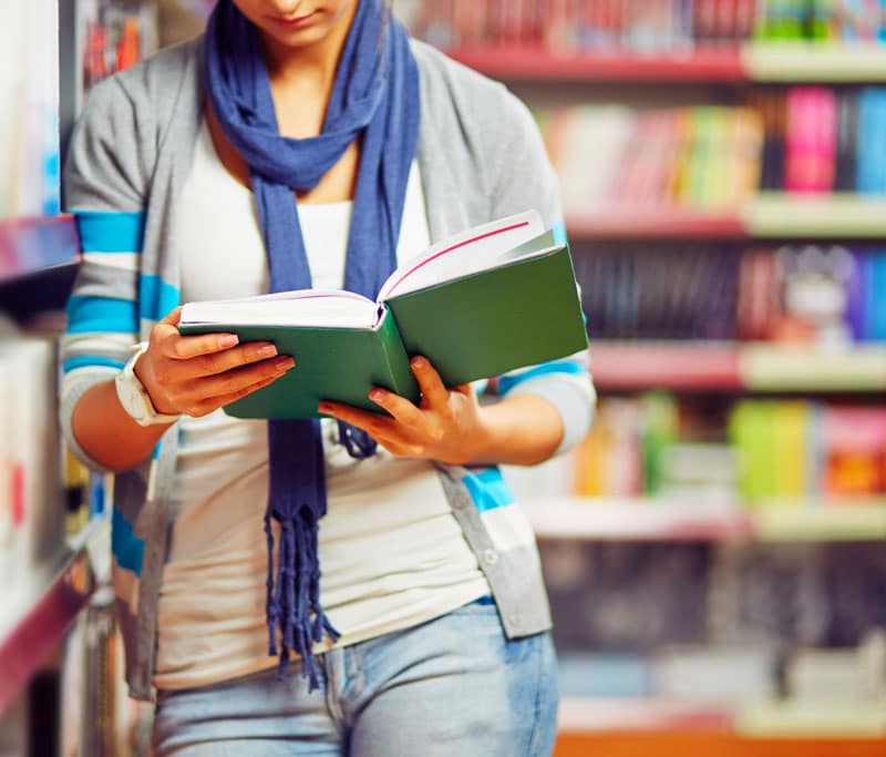A woman reading a book from a library