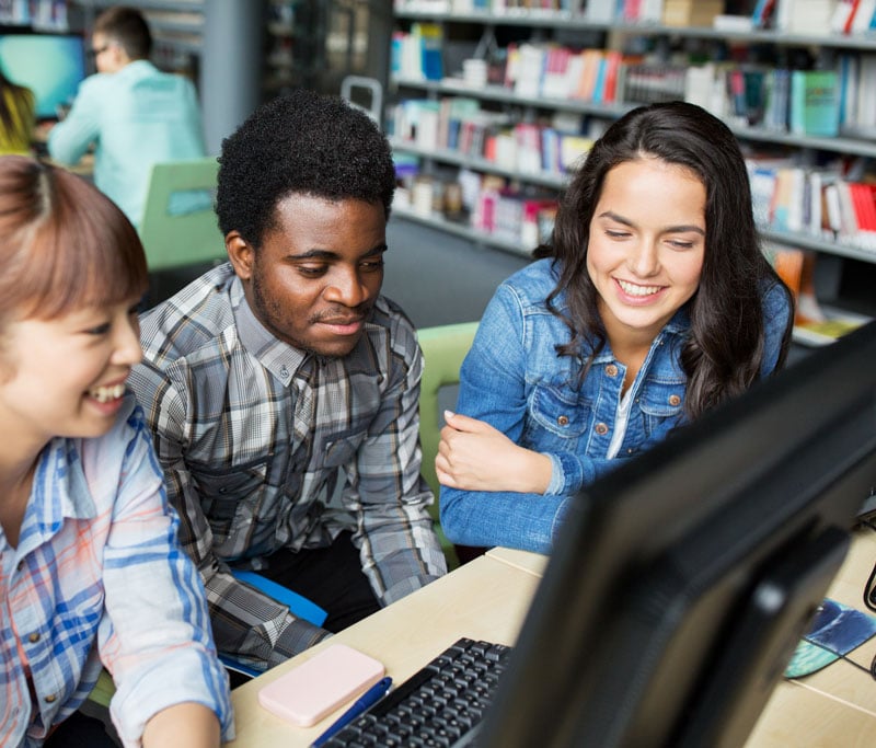 A group of young adult students surrounding a computer at the Lifelong Learning and Workforce Development program of the State College of Florida