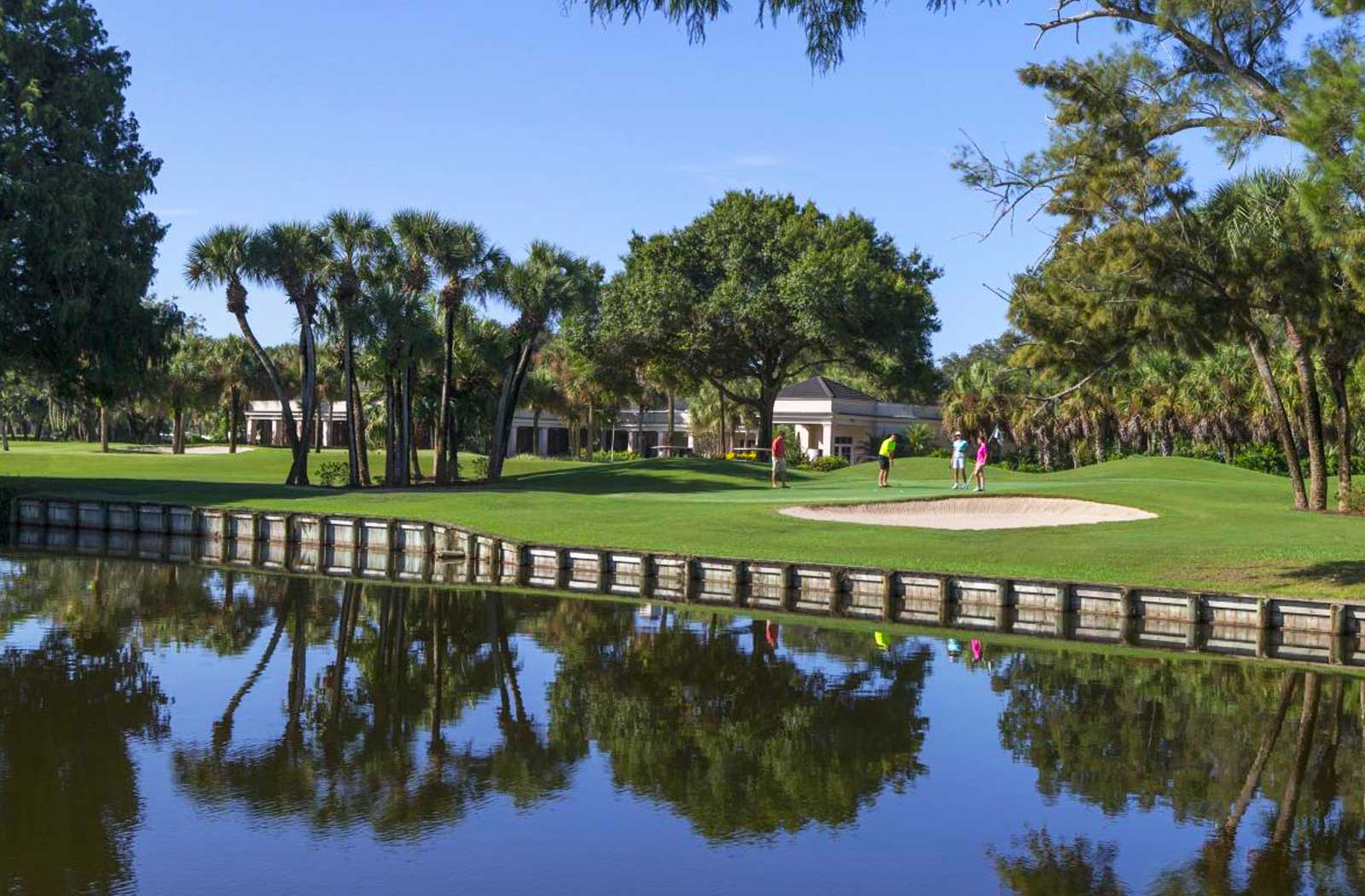An image of the golf course taken from the other side of a water feature, that beautifully reflects the surrounding trees