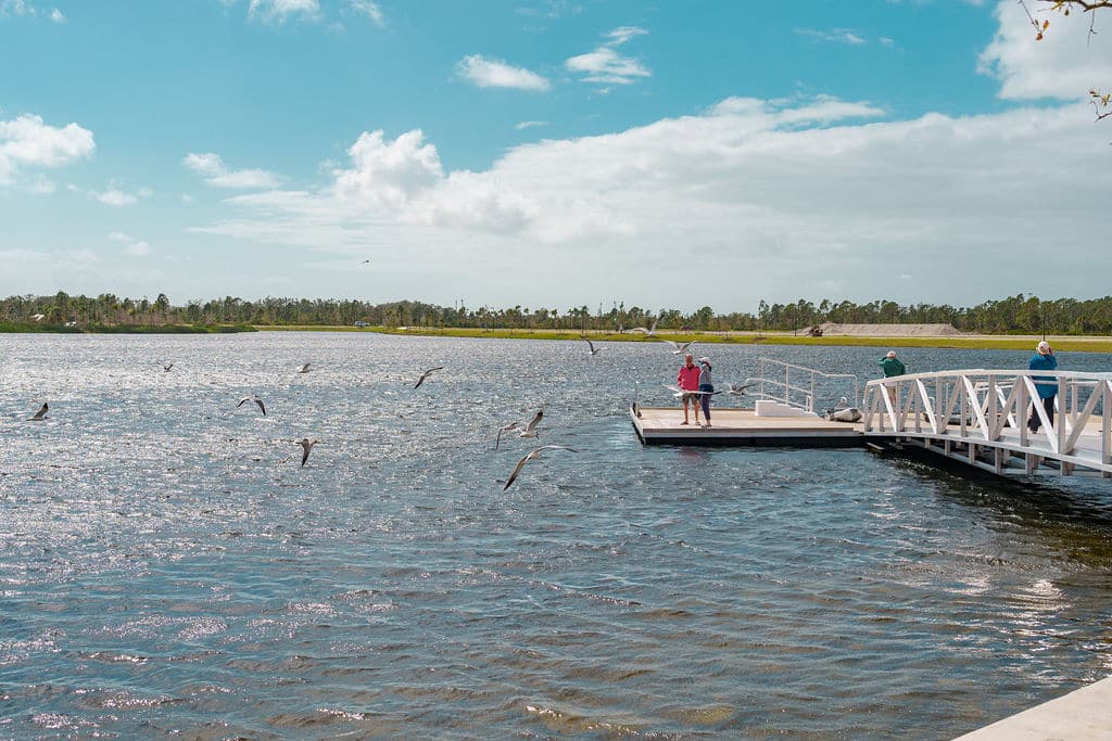 A Lake with people standing on a pier extending into the water
