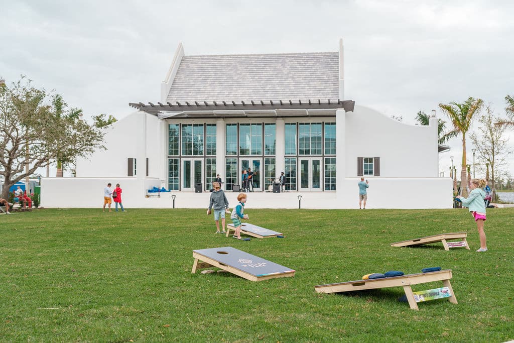A lawn area with cornhole boards with Solis Hall in the background