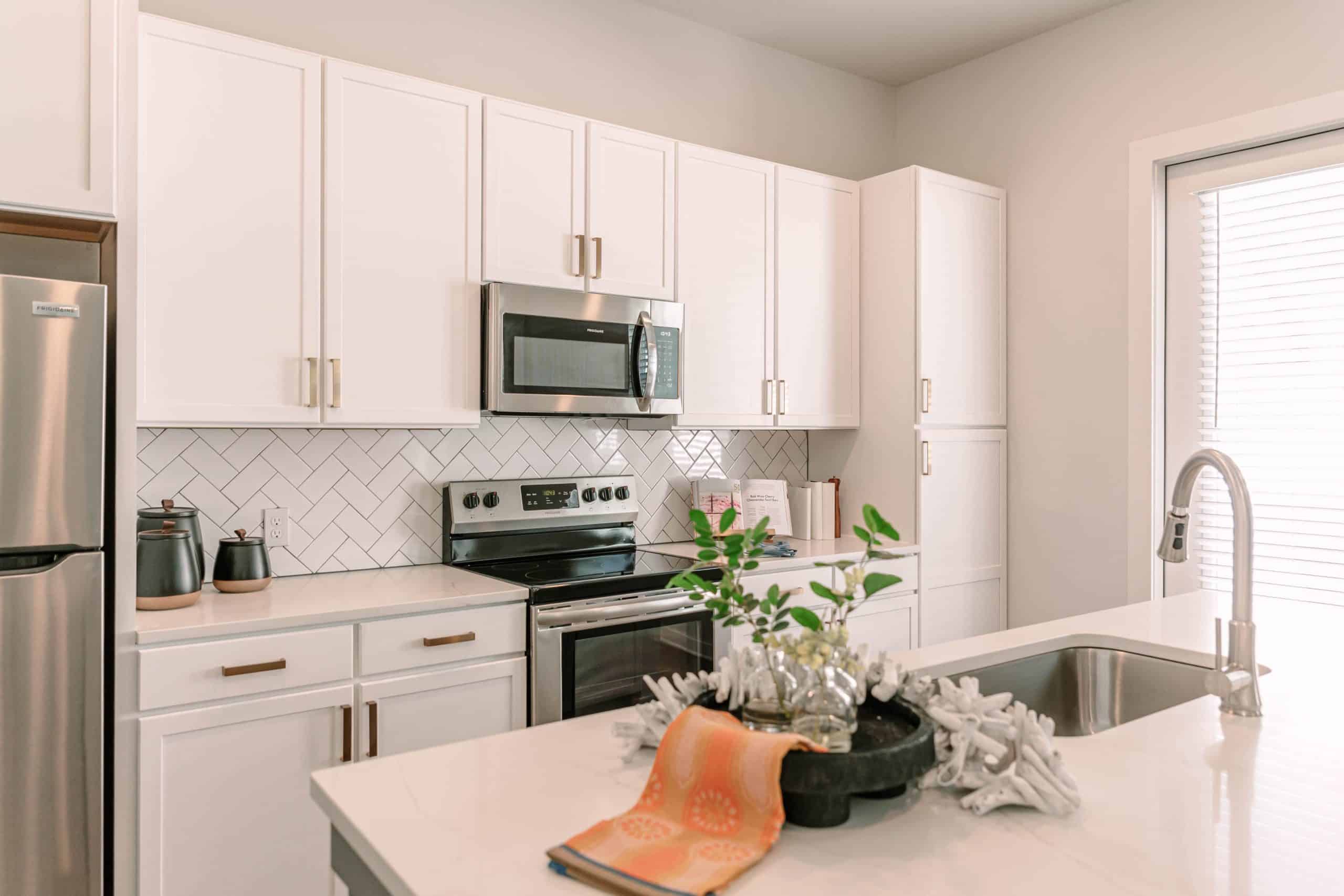 A kitchen with white finishings, a kitchen island and stainless steel appliances