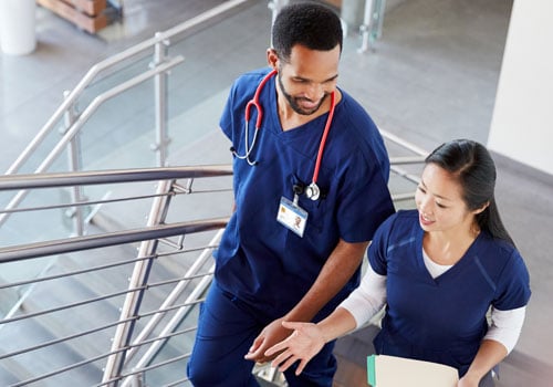 Two health practitioners in scrubs walking up stairs at Sarasota Memorial’s North Port ER and Health Care