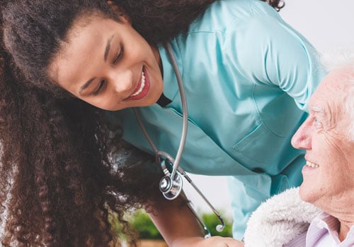 A nurse in scrubs talking to a senior man in a wheelchair at Sarasota Memorial Hospital — Venice