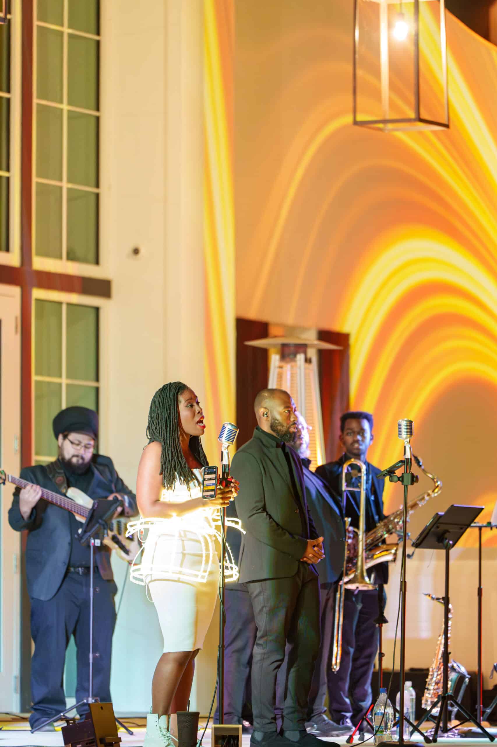 A band and siingers standing up on a stage at Solis Hall