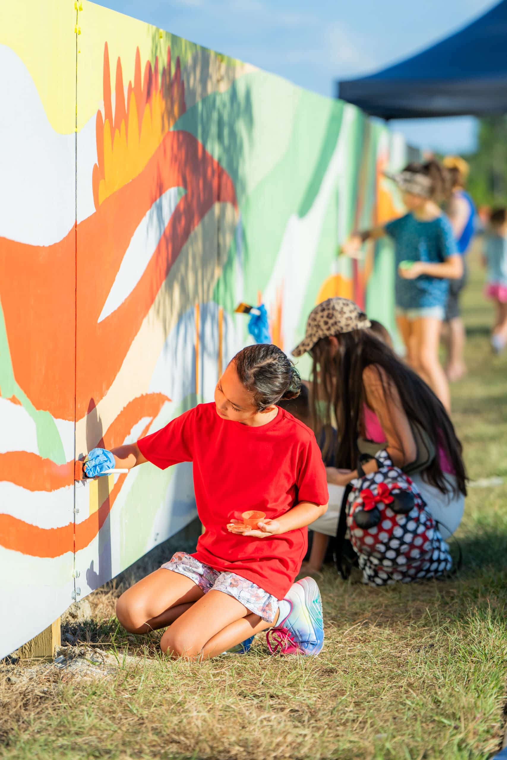 Two young girls painting a wall with bright colorful images