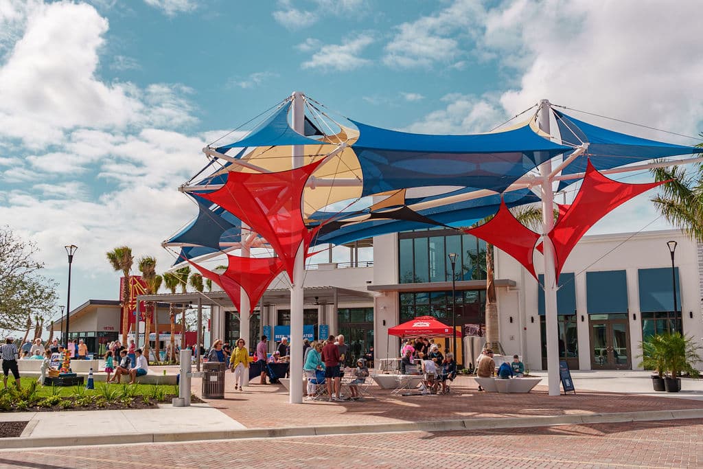 An outdoor park with several benches, and blue, red and yellow triangular sun covers layered in a fun abstract way outside the school