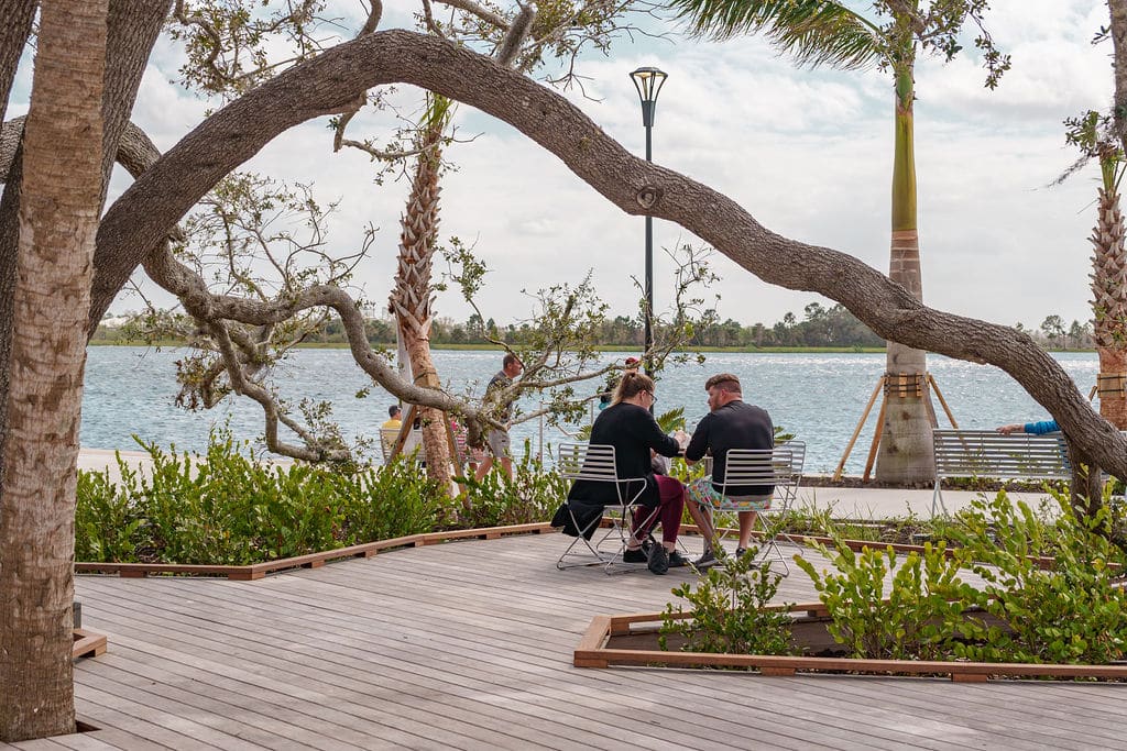 Two people sitting at an outdoor table by the water