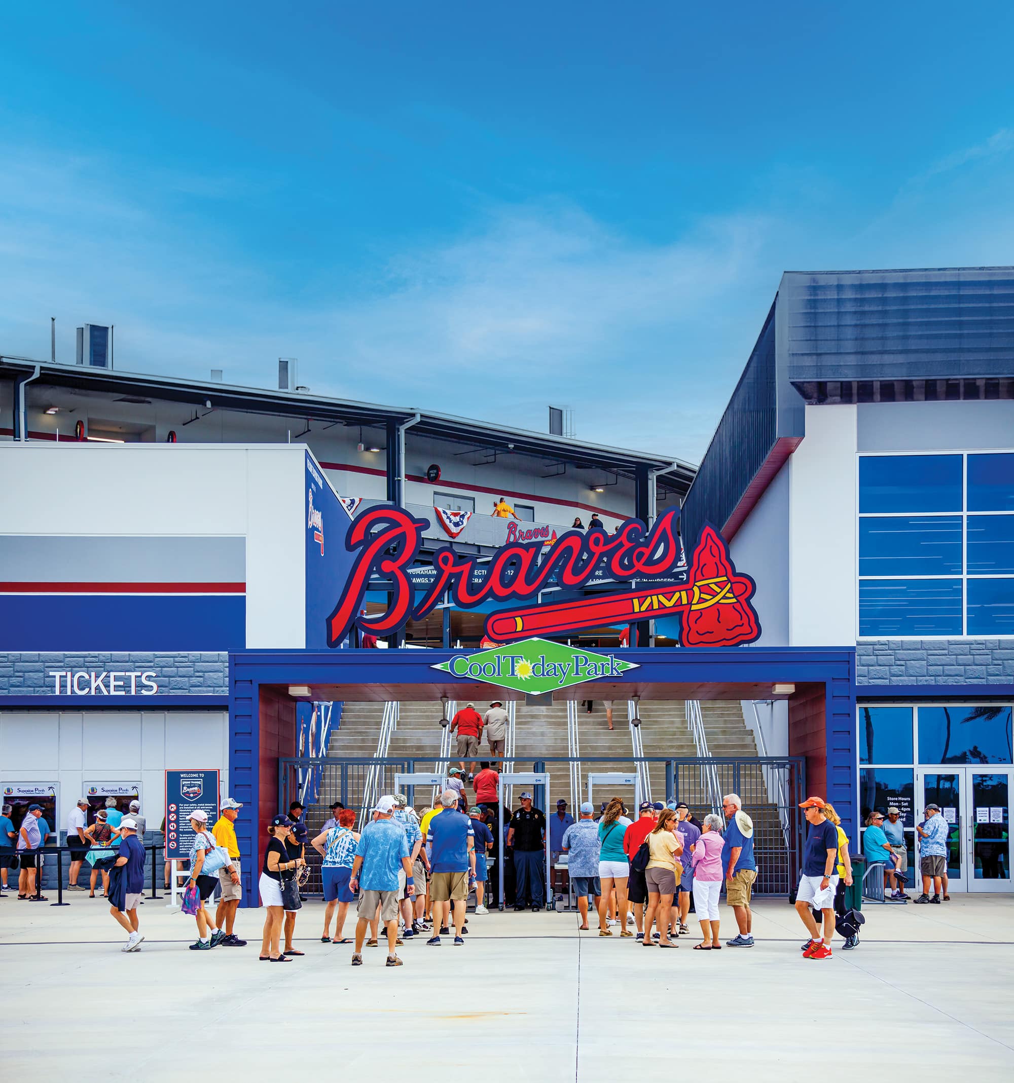 Crowd entering CoolToday Park, home of the Braves, on a sunny day, with a large team sign above the entrance